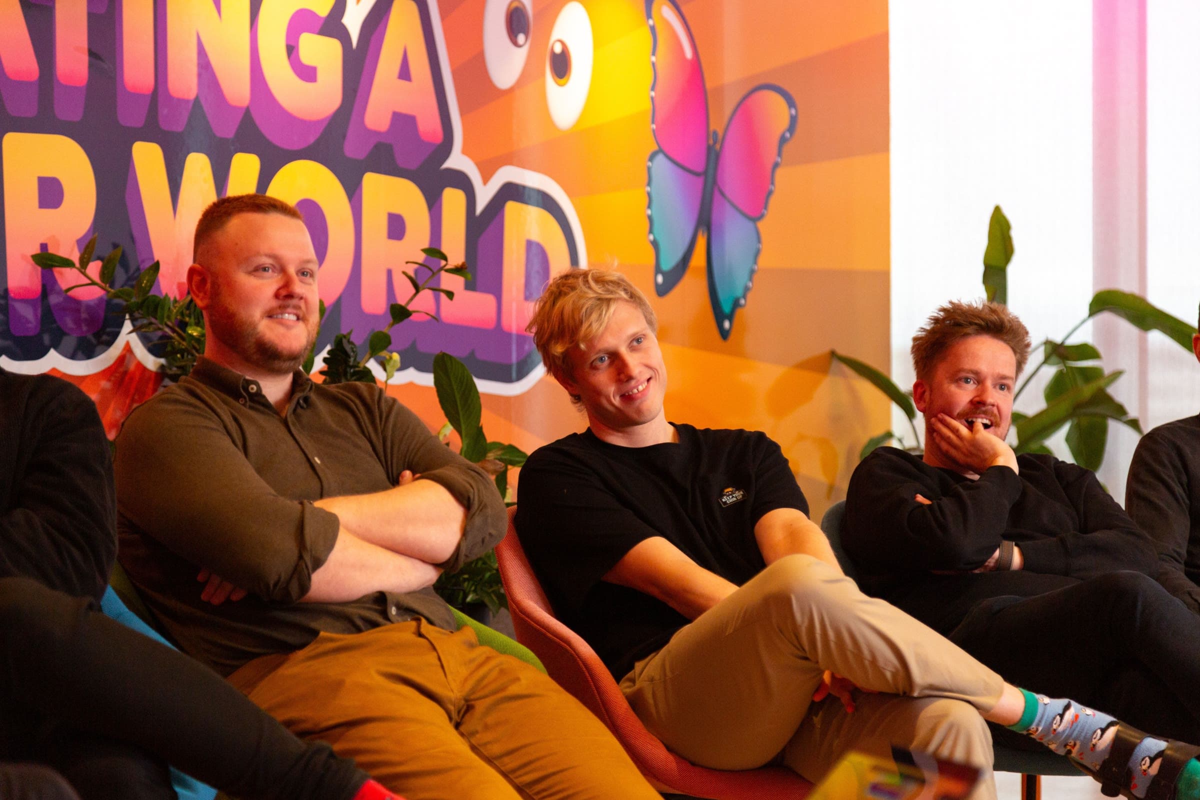 Three of the team slouched in armchairs, laughing at something off camera